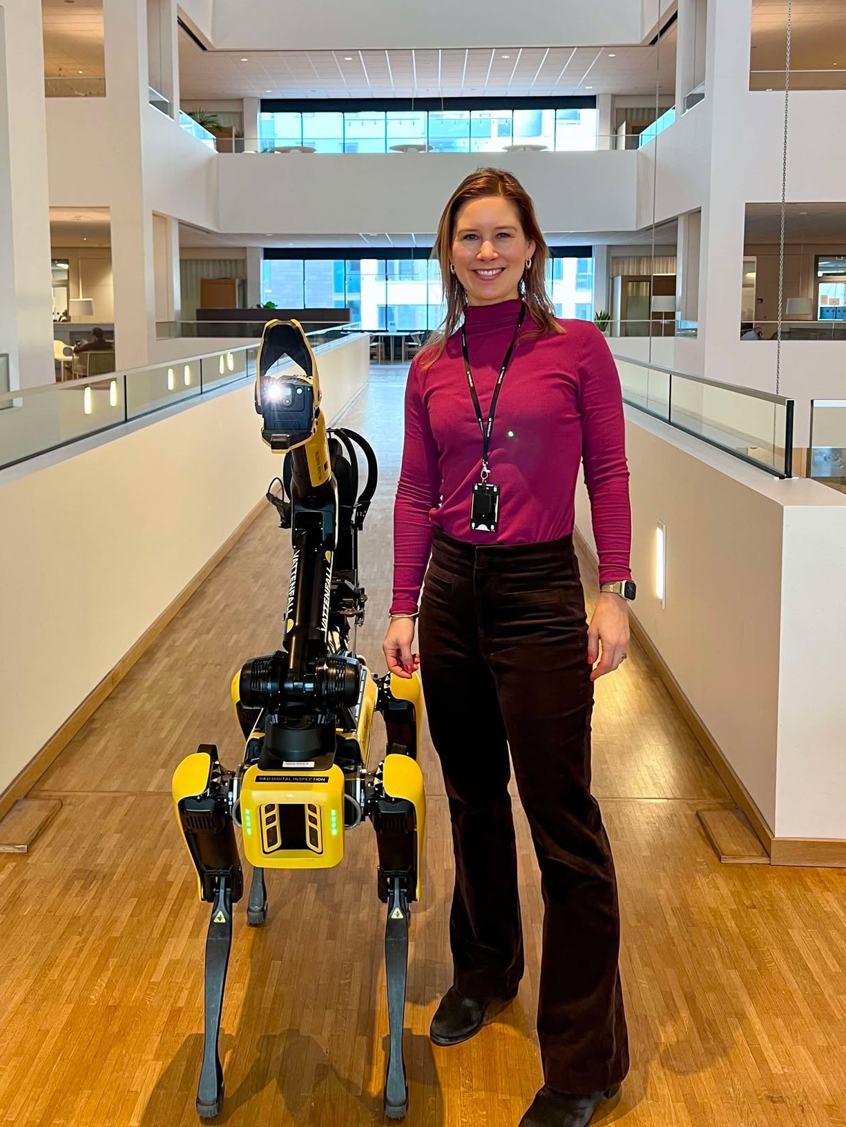 Hanna Radtke Bergström standing beside a robot dog in a modern office atrium